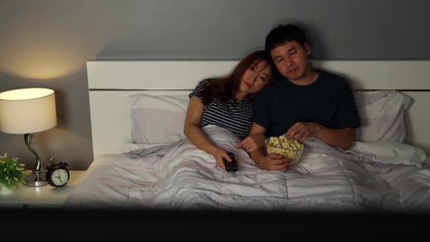 若いカップルはテレビを見て夜にベッドでポップコーンを食べて — ストック動画