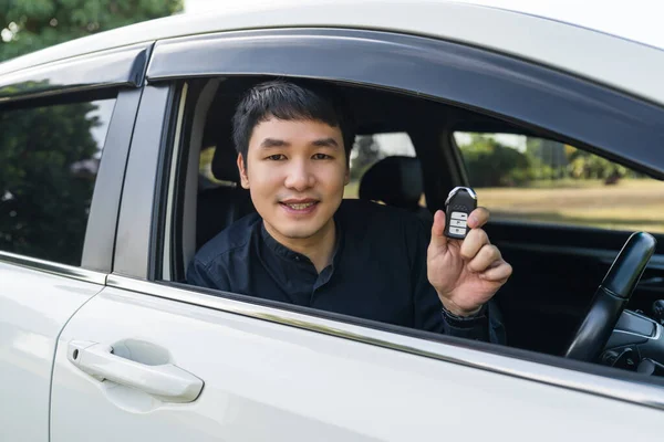 young man with smart key remote in a car