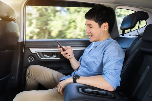 Joven Feliz Usando Teléfono Inteligente Mientras Está Sentado Asiento Trasero — Foto de Stock