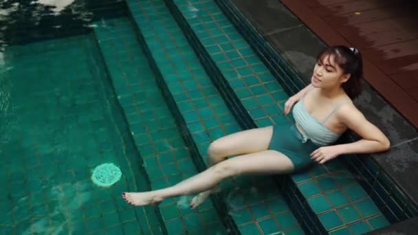 年轻女子坐在游泳池的楼梯上 — 图库视频影像