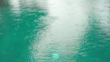 Yağmur damlalarının yüzeye düştüğü su havuzunun yavaş akışı