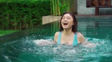 Yüzme havuzunda su sıçratan neşeli kadının yavaş çekimleri.