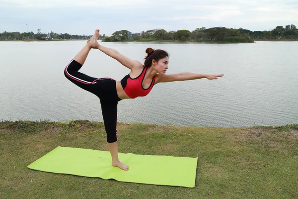 Mladá žena dělá jógu cvičení v parku — Stock fotografie