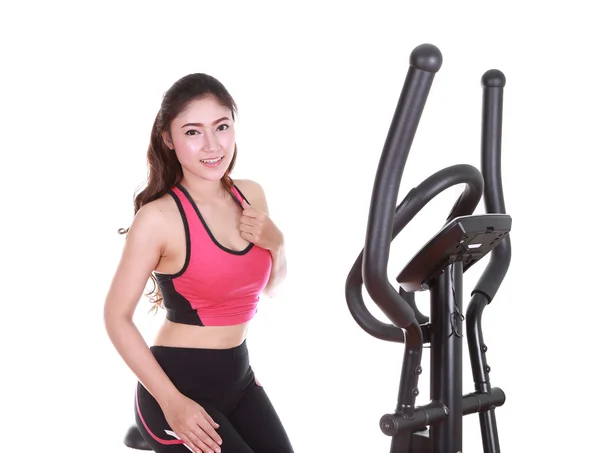 Ung kvinde laver øvelser med træningsmaskine - Stock-foto