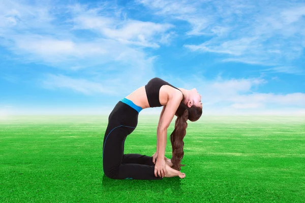 Frau macht Yoga-Übungen auf Gras mit Himmel — Stockfoto