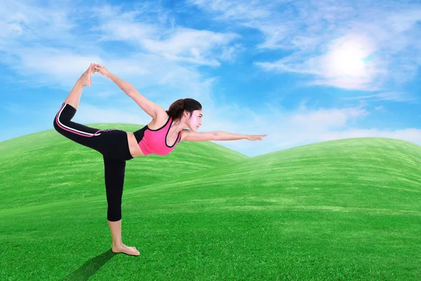 Vrouw doen yoga oefening op gras met sky — Stockfoto