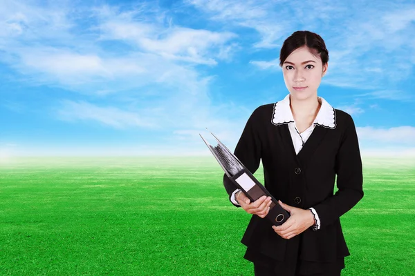 Affärskvinna hålla mappen dokument med grönt gräs fält — Stockfoto