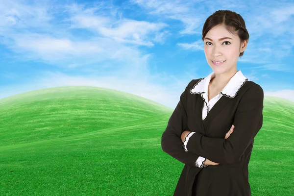 Business woman, cross arms, with green grass field and blue s — стоковое фото