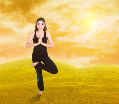 gün batımında Yoga egzersiz gökyüzü ile çimenlerin üzerinde yaparak kadın