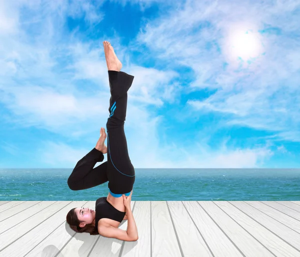 Mujer haciendo ejercicio de yoga sobre suelo de madera con mar y cielo — Foto de Stock