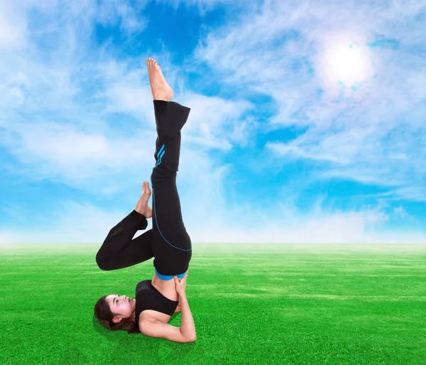 Vrouw doen yoga oefening op gras met sky — Stockfoto