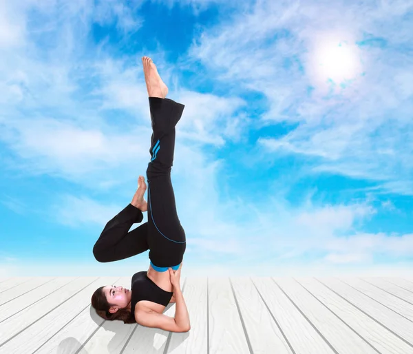Frau macht Yoga-Übung auf Holzboden mit Himmel — Stockfoto