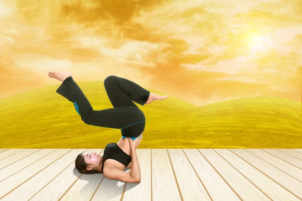 Woman doing yoga exercise on wood floor with field at sunset — Stock Photo, Image