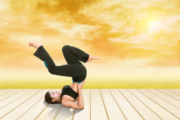 Kobieta robi ćwiczenia jogi na podłogi z drewna z pola na zachodzie słońca — Zdjęcie stockowe