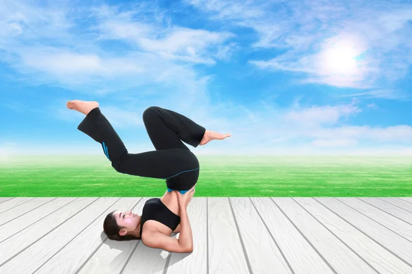 Frau macht Yoga-Übungen auf Holzboden mit grünem Gras und Himmel — Stockfoto