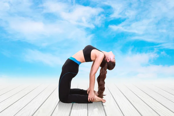 Jonge vrouw doen yoga oefening op houten vloer — Stockfoto