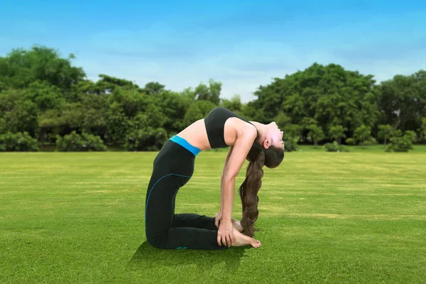 Mujer haciendo ejercicio de yoga sobre hierba con cielo — Foto de Stock