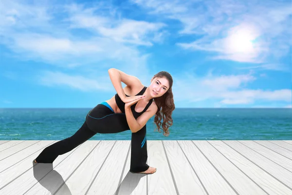 Mulher fazendo exercício de ioga no chão de madeira com mar e céu — Fotografia de Stock