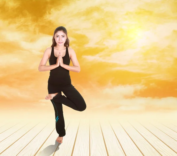 Vrouw doen yoga oefening op houten vloer bij zonsondergang — Stockfoto