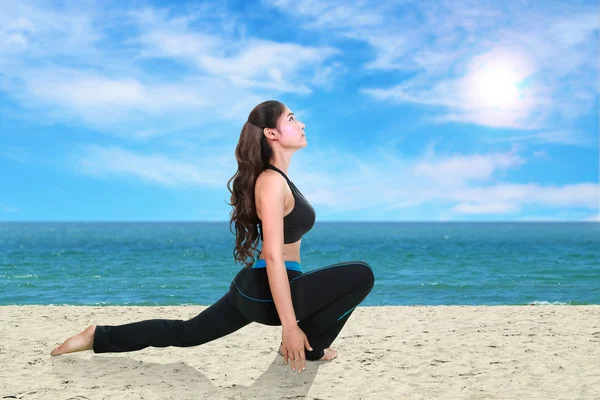 Mujer haciendo ejercicio de yoga en la playa — Foto de Stock