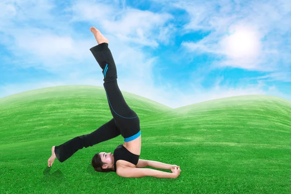 Woman doing yoga exercise on grass with sky — Stock Photo, Image