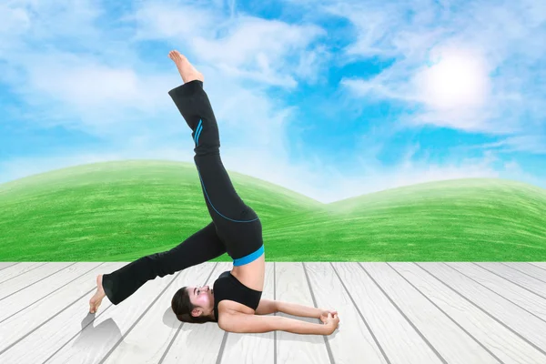 Mulher fazendo exercício de ioga no chão de madeira com grama verde e céu — Fotografia de Stock