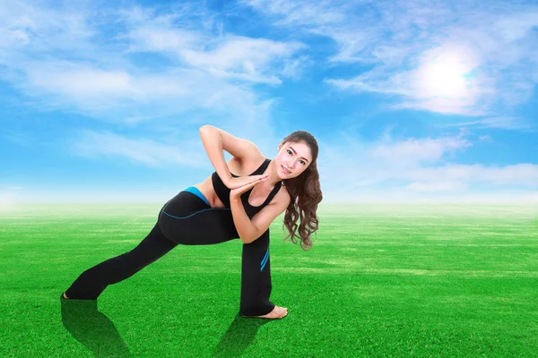 Donna che fa esercizio di yoga su erba con cielo — Foto Stock