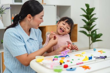 toddler girl with her mother sculpting from plasticine at home