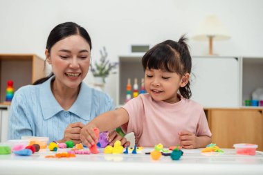 toddler girl with her mother sculpting from plasticine at home
