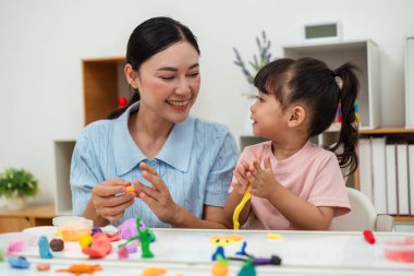 toddler girl with her mother sculpting from plasticine at home