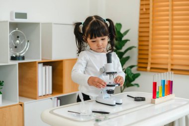 toddler girl scientist placing microscope slides with specimen. learning science at home