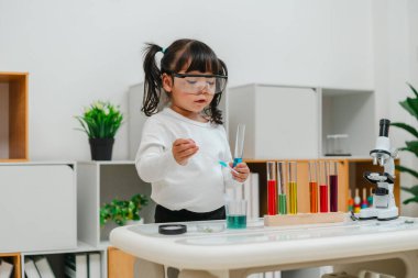 toddler girl scientist study using pipette dropping liquid with test tube and beaker. learning science