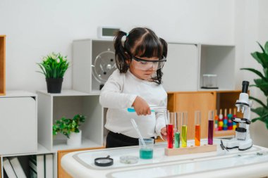toddler girl scientist making chemical test with test tube and beaker. learning science at home