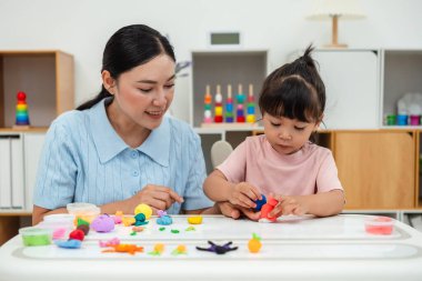 toddler girl with her mother sculpting from plasticine at home