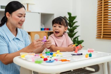 toddler girl with her mother sculpting from plasticine at home