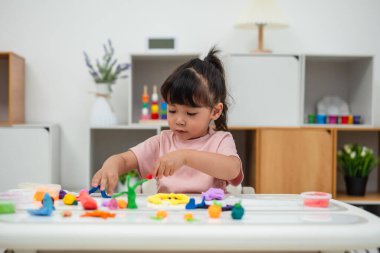 toddler girl with sculpting from plasticine at home