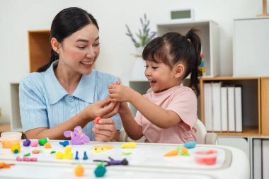toddler girl with her mother sculpting from plasticine at home