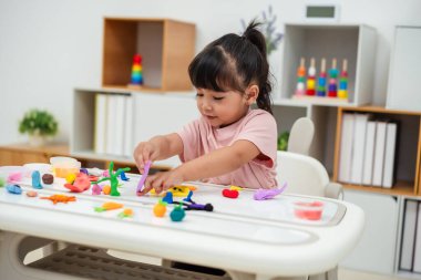 toddler girl with sculpting from plasticine at home