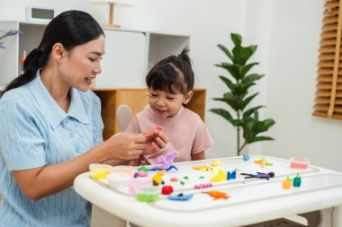 toddler girl with her mother sculpting from plasticine at home