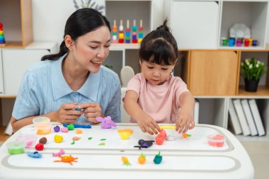 toddler girl with her mother sculpting from plasticine at home