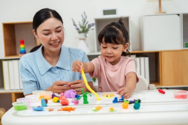 toddler girl with her mother sculpting from plasticine at home