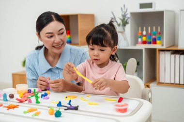toddler girl with her mother sculpting from plasticine at home