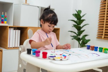 Evdeki bir gazetede suluboya resim yapan mutlu bir kız.