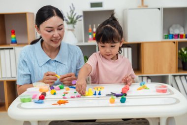 toddler girl with her mother sculpting from plasticine at home