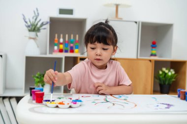 Evdeki bir gazetede suluboya resim yapan mutlu bir kız.