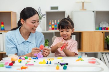 toddler girl with her mother sculpting from plasticine at home