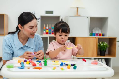 toddler girl with her mother sculpting from plasticine at home