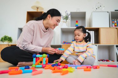 Mutlu bebek kız ve anne evde renkli manyetik inşaat oyuncağı oynuyorlar.