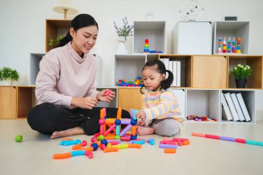 Mutlu bebek kız ve anne evde renkli manyetik inşaat oyuncağı oynuyorlar.