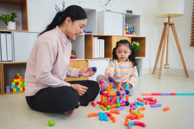 Mutlu bebek kız ve anne evde renkli manyetik inşaat oyuncağı oynuyorlar.